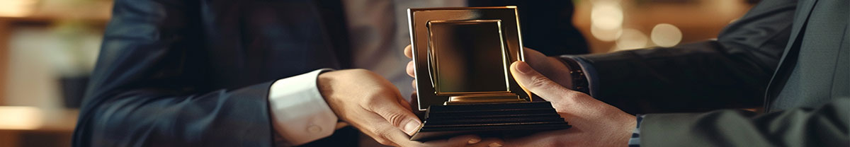 Díjazottak oldal header képe, ami illusztráció a tartalomhoz és egy elismerés plakett átadását mutatja.